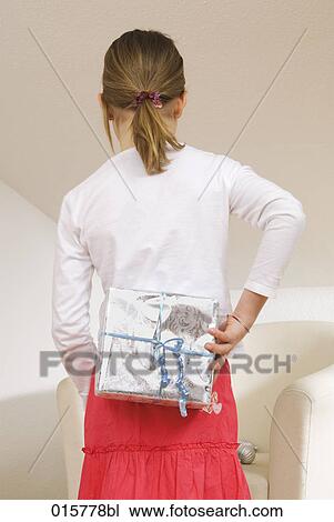 rear view of girl hiding christmas present behind her back View Large Photo Image Stock Image - rear view of girl hiding christmas present behind her back. Fotosearch