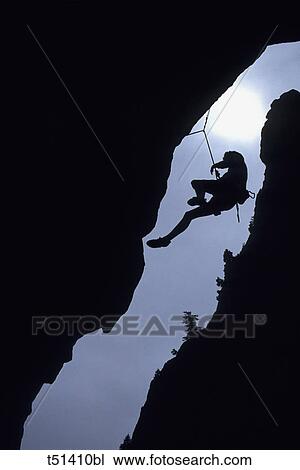 Silhouette of rock climber hanging from cliff face View Large Photo Image Stock Image - Silhouette of rock climber hanging from cliff face. Fotosearch