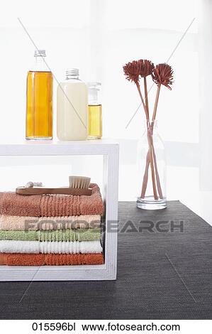 Stock Image - still life of towels in shelf cosmetic bottles and flowers in vase. Fotosearch