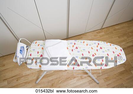 Stock Image - still life of white towels and flat iron on ironing board. Fotosearch