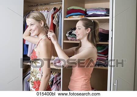 teenage girl helping her friend getting dressed in front of open wardrobe View Large Photo Image Stock Image - teenage girl helping her friend getting dressed in front of open wardrobe. Fotosearch