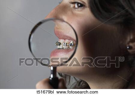 Stock Image - Teenage girl with lens on her mouth. Fotosearch