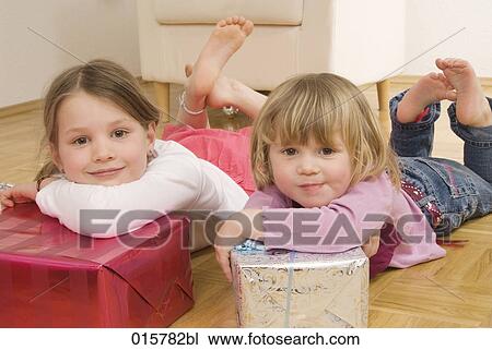 two sisters lying on floor with christmas presents View Large Photo Image Stock Image - two sisters lying on floor with christmas presents. Fotosearch