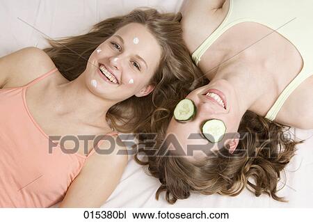 two smiling young women lying on bed undergoing facial treatment View Large Photo Image Stock Image - two smiling young women lying on bed undergoing facial treatment. Fotosearch