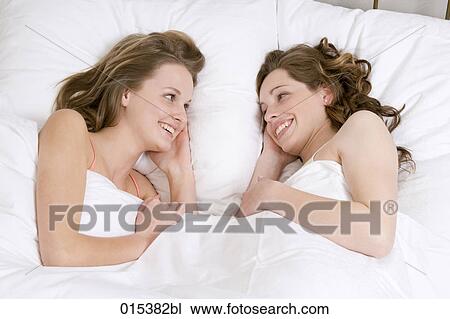 two young women lying in bed smiling at each other View Large Photo Image Stock Image - two young women lying in bed smiling at each other. Fotosearch