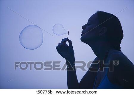 Stock Image - Woman blowing bubbles. Fotosearch
