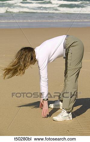 Stock Image - Woman doing exercises on the beach. Fotosearch