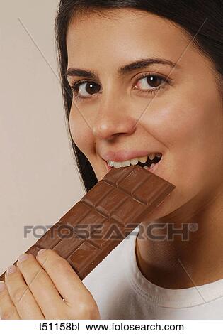 Woman eating a bar of chocolate View Large Photo Image Stock Image - Woman eating a bar of chocolate. Fotosearch