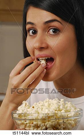 Stock Image - Woman eating popcorn. Fotosearch