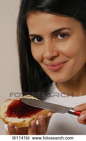 Woman eating spreading jam on bread View Large Photo Image Stock Image - Woman eating spreading jam on bread. Fotosearch
