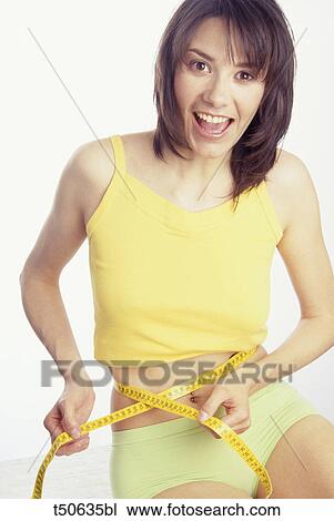 Woman holding tape measure around waist View Large Photo Image Stock Image - Woman holding tape measure around waist. Fotosearch