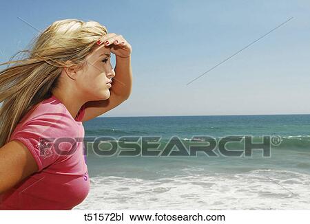 Stock Image - Woman on beach looking towards sea. Fotosearch