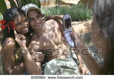 Woman taking picture to a young couple with mobile phone View Large Photo Image Stock Image - Woman taking picture to a young couple with mobile phone. Fotosearch