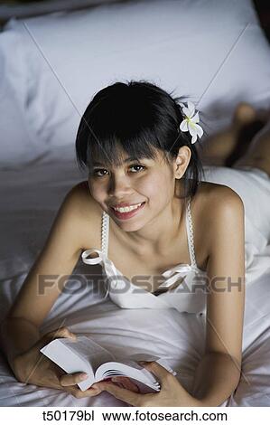 Woman's portrait lying on bed with book View Large Photo Image Stock Image - Woman's portrait lying on bed with book. Fotosearch