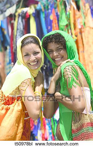 Women playfully trying on scafs in outdoor market View Large Photo Image Stock Image - Women playfully trying on scafs in outdoor market. Fotosearch