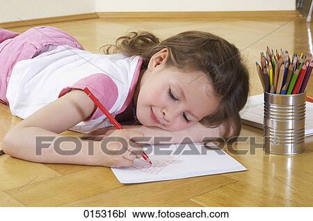 Stock Image - young girl lying on floor drawing. Fotosearch