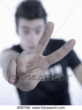 Stock Image - Young man giving peace sign. Fotosearch