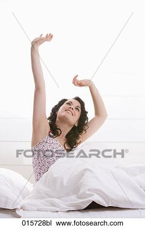 young woman sitting in bed stretching herself View Large Photo Image Stock Image - young woman sitting in bed stretching herself. Fotosearch