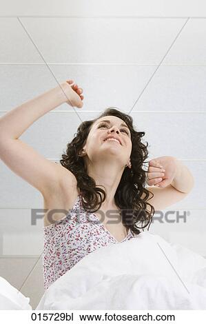 young woman sitting in bed stretching herself View Large Photo Image Stock Image - young woman sitting in bed stretching herself. Fotosearch