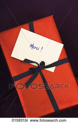 Stock Image - close-up of red present with french note merci. Fotosearch