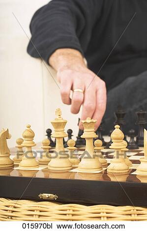 Stock Image - detail of man playing chess at home. Fotosearch