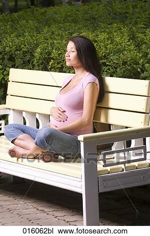 full body portrait of pregnant young woman sitting on park bench View Large Photo Image Stock Image - full body portrait of pregnant young woman sitting on park bench. Fotosearch