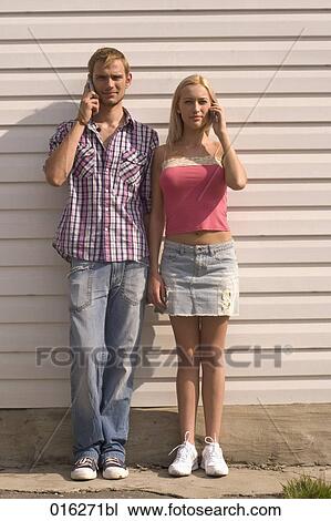 full body portrait of young couple standing against wall using mobile phones View Large Photo Image Stock Image - full body portrait of young couple standing against wall using mobile phones. Fotosearch