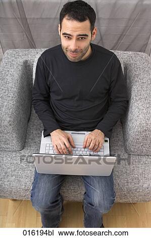 high angle portrait of young man working with laptop computer at home View Large Photo Image Stock Image - high angle portrait of young man working with laptop computer at home. Fotosearch