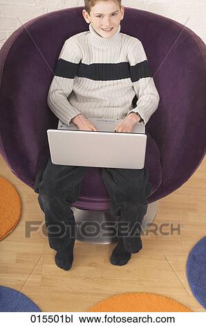 high angle view of young boy sitting in arm chair with laptop computer View Large Photo Image Stock Image - high angle view of young boy sitting in arm chair with laptop computer. Fotosearch
