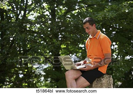 Stock Image - Man using laptop outdoors . Fotosearch