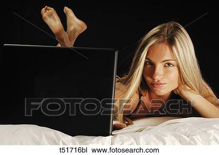 Portrait of a woman lying on bed with laptop View Large Photo Image Stock Image - Portrait of a woman lying on bed with laptop . Fotosearch