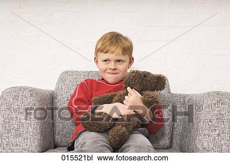 Stock Image - portrait of young boy cuddling teddy bear. Fotosearch