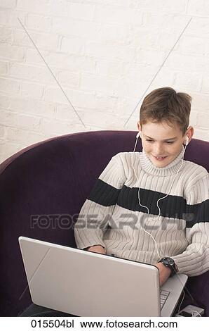 portrait of young boy listening to music on ipod and typing on laptop computer View Large Photo Image Stock Image - portrait of young boy listening to music on ipod and typing on laptop computer. Fotosearch