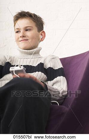 Stock Image - portrait of young boy listening to music on ipod. Fotosearch