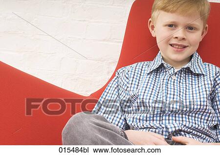 Stock Image - portrait of young boy sitting in arm chair. Fotosearch