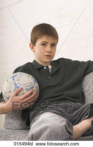 portrait of young boy sitting in arm chair holding football View Large Photo Image Stock Image - portrait of young boy sitting in arm chair holding football. Fotosearch