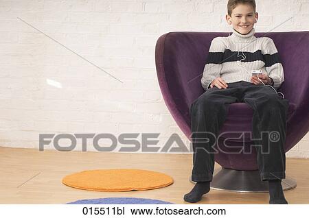 portrait of young boy sitting in arm chair listening to music on ipod View Large Photo Image Stock Image - portrait of young boy sitting in arm chair listening to music on ipod. Fotosearch