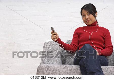portrait of young japanese woman sitting in arm chair listening to music on ipod View Large Photo Image Stock Image - portrait of young japanese woman sitting in arm chair listening to music on ipod. Fotosearch