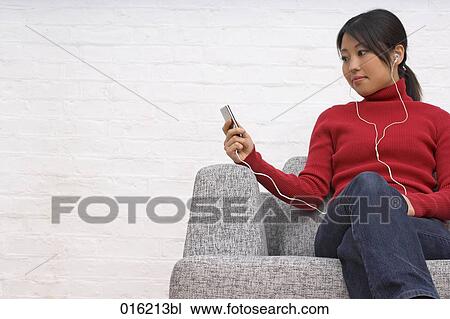 portrait of young japanese woman sitting in arm chair listening to music on ipod View Large Photo Image Stock Image - portrait of young japanese woman sitting in arm chair listening to music on ipod. Fotosearch