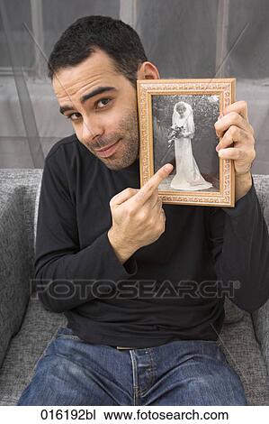 portrait of young man holding photography of woman in wedding dress View Large Photo Image Stock Image - portrait of young man holding photography of woman in wedding dress. Fotosearch