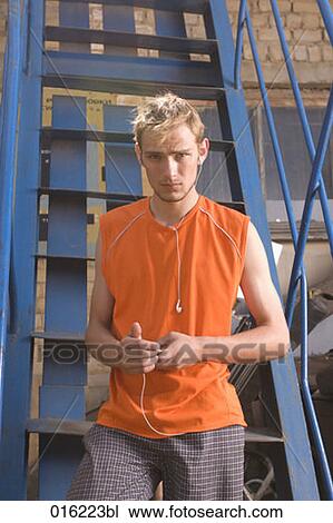 portrait of young man in orange t-shirt listening to music on mp3 player View Large Photo Image Stock Image - portrait of young man in orange t-shirt listening to music on mp3 player. Fotosearch
