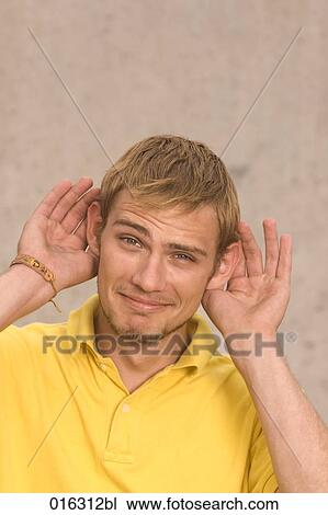 portrait of young man jokingly holding his hands to the ears View Large Photo Image Stock Image - portrait of young man jokingly holding his hands to the ears. Fotosearch