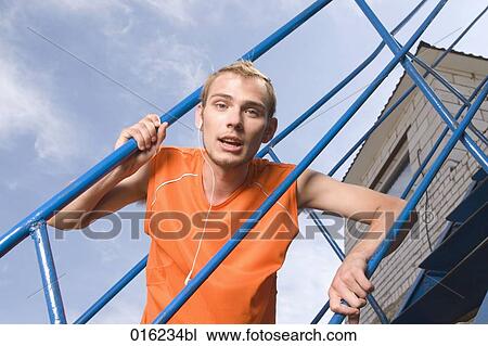 portrait of young man looking through railing listening to music on mp3 player View Large Photo Image Stock Image - portrait of young man looking through railing listening to music on mp3 player. Fotosearch