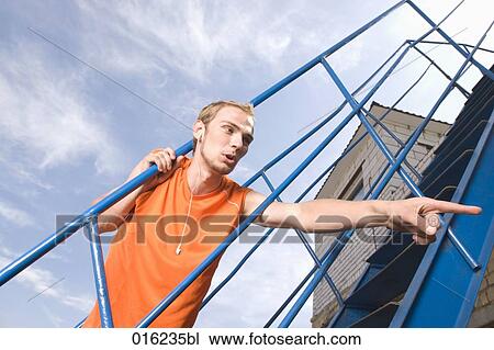 portrait of young man looking through railing pointing with index finger View Large Photo Image Stock Image - portrait of young man looking through railing pointing with index finger. Fotosearch