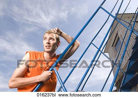 Stock Image - portrait of young man on stairs looking into distance. Fotosearch