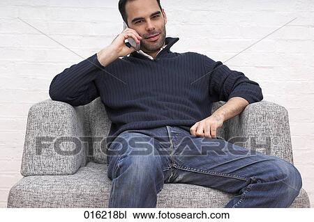 portrait of young man sitting in arm chair talking on mobile phone View Large Photo Image Stock Image - portrait of young man sitting in arm chair talking on mobile phone. Fotosearch