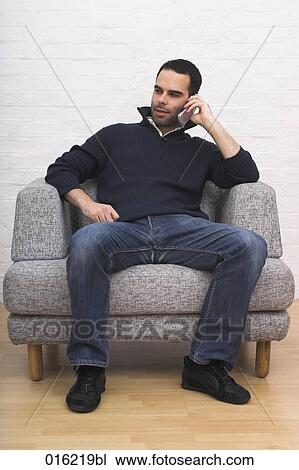 portrait of young man sitting in arm chair talking on mobile phone View Large Photo Image Stock Image - portrait of young man sitting in arm chair talking on mobile phone. Fotosearch