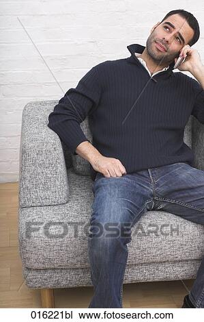 portrait of young man sitting in arm chair talking on mobile phone View Large Photo Image Stock Image - portrait of young man sitting in arm chair talking on mobile phone. Fotosearch