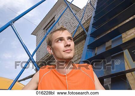 portrait of young man sitting on stairs listening to music on mp3 player View Large Photo Image Stock Image - portrait of young man sitting on stairs listening to music on mp3 player. Fotosearch