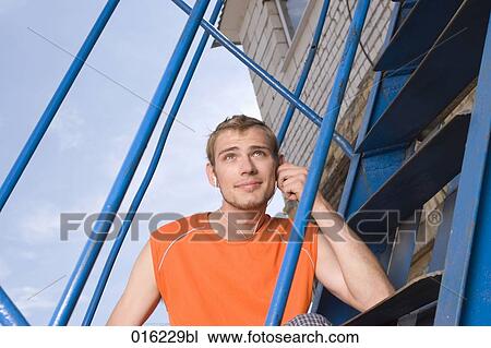 portrait of young man sitting on stairs listening to music on mp3 player View Large Photo Image Stock Image - portrait of young man sitting on stairs listening to music on mp3 player. Fotosearch